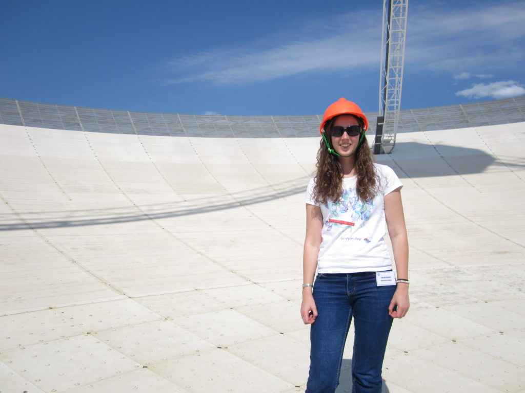 Photograph of Sarah Reeves on the surface of a large radio telescope dish.